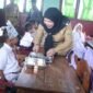 Wali Kota Eva Dwiana bercengkerama dengan seorang murid seputar menu MBG yang disajikan. (Foto: ist)